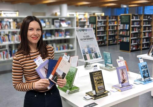 Veronica Talgø ved Trondheim folkebibliotek foran en utstilling på biblioteket der innhold fra Forrigebok er brukt aktivt.